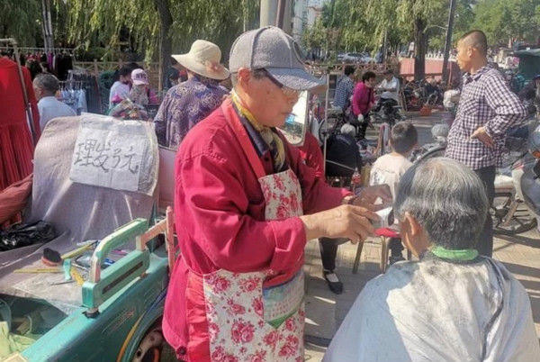 自閉癥單親媽媽擺地攤十幾年，帶孩子為人理發(fā)